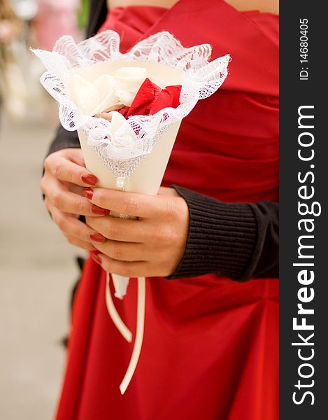 Close-up of a bridesmaid's arms holding a wedding paper bag with rose petals. Close-up of a bridesmaid's arms holding a wedding paper bag with rose petals