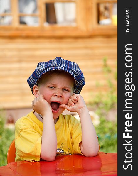 Boy yawing while waiting for his dinner outdoor. Boy yawing while waiting for his dinner outdoor