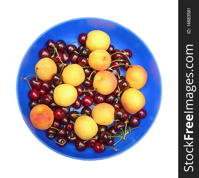 Ripe apricots and cherries in the blue dish are shown in the picture. Ripe apricots and cherries in the blue dish are shown in the picture.