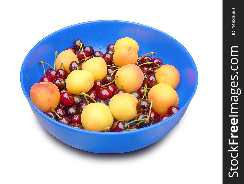 Ripe apricots and cherries in the blue dish are shown in the picture. Ripe apricots and cherries in the blue dish are shown in the picture.