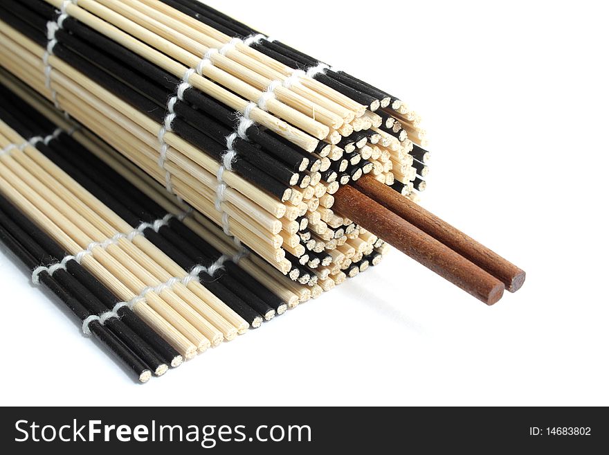 Rolled bamboo mat with a pair of chopsticks inside it on white background. Rolled bamboo mat with a pair of chopsticks inside it on white background
