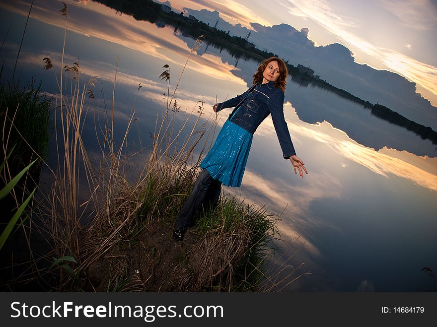 Young woman spreading arms at sunset lake. Young woman spreading arms at sunset lake