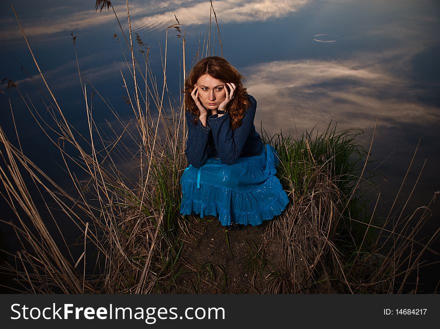 Lonely young woman at sunset lake. Lonely young woman at sunset lake