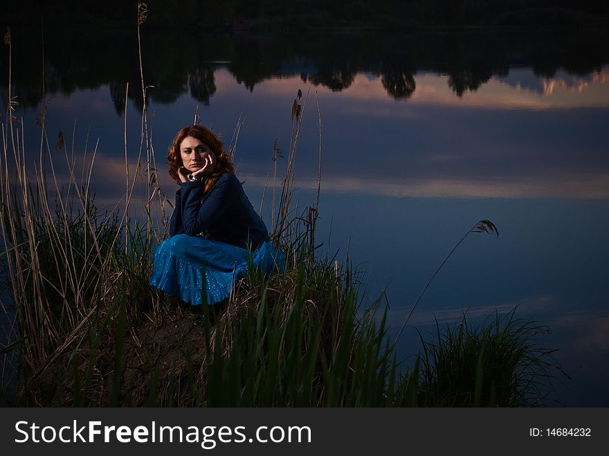 Lonely young woman at sunset lake. Lonely young woman at sunset lake