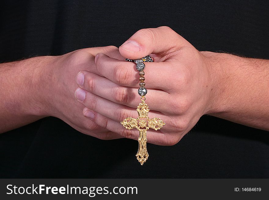 The cross in man's hands, the man is dressed in dark clothes.
