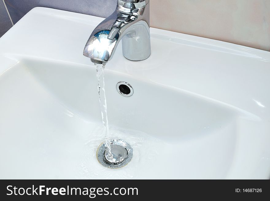 White washstand with flowing clean transparent water. White washstand with flowing clean transparent water