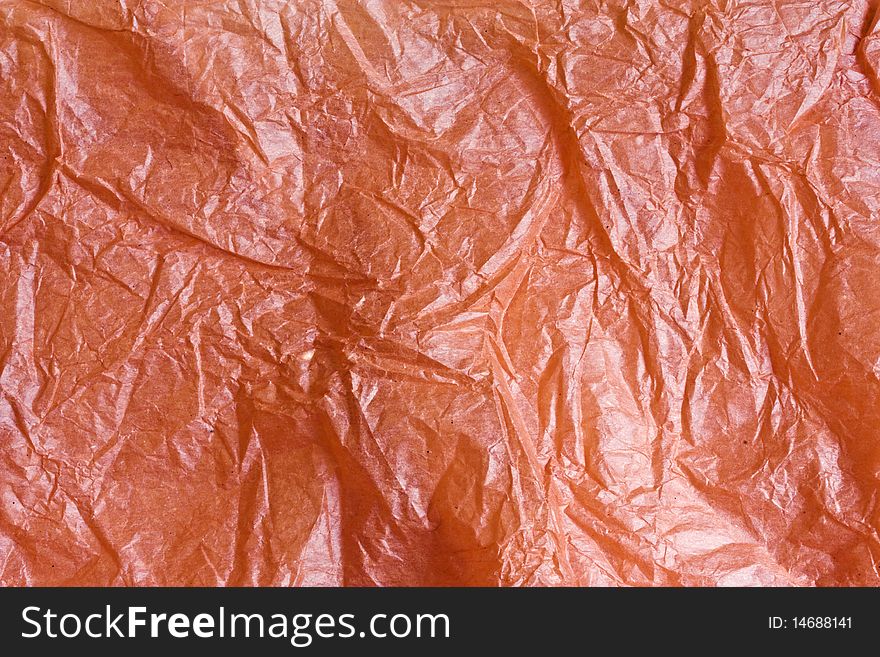 A closeup picture of scrunched up shiny orange tissue paper