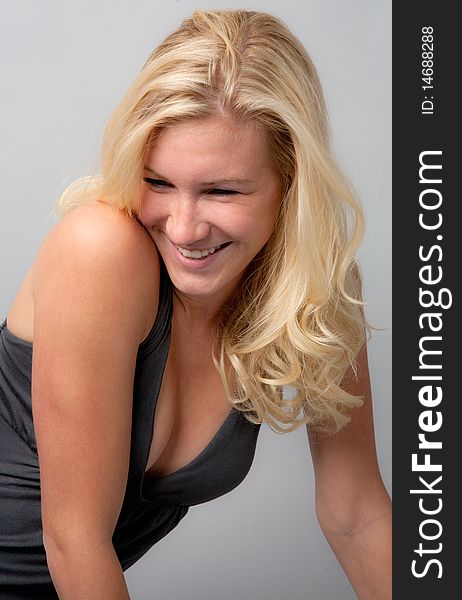 A candid-looking portrait of a pretty young model with blond hair laughing happily. A candid-looking portrait of a pretty young model with blond hair laughing happily