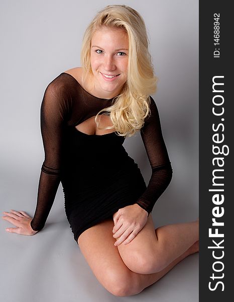 Portrait of a pretty young model wearing a black dress with sheer arms and smiling happily. Portrait of a pretty young model wearing a black dress with sheer arms and smiling happily