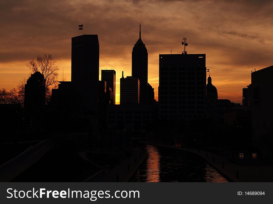 Silhouette of skyscrapers set against a partly cloudy sky during sunrise. Silhouette of skyscrapers set against a partly cloudy sky during sunrise.