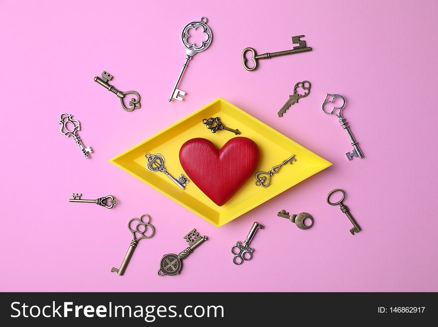 Flat lay composition with different keys and decorative heart on color background
