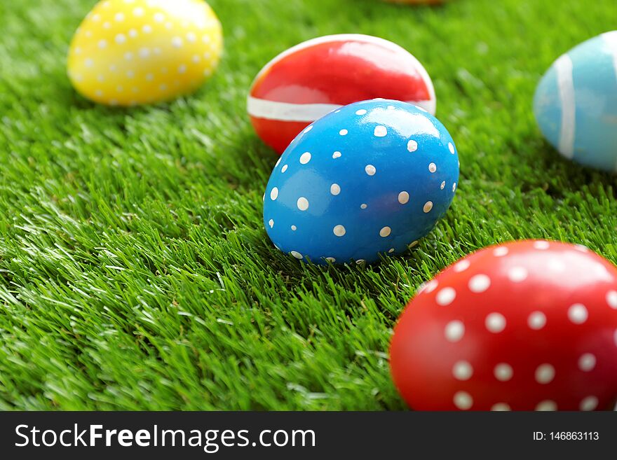 Colorful painted Easter eggs on green grass, space for text