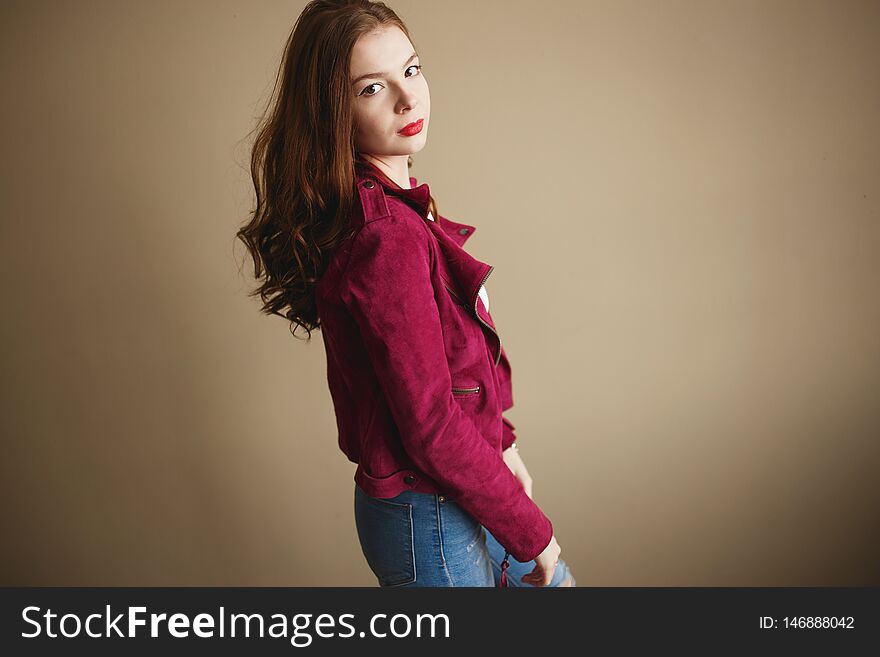 Young hipster woman clothed in magenta jacket. Beautiful eyes, long brown curly hair.