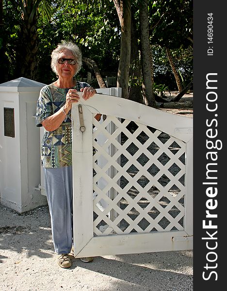 Senior Woman Standing by Open White Gate