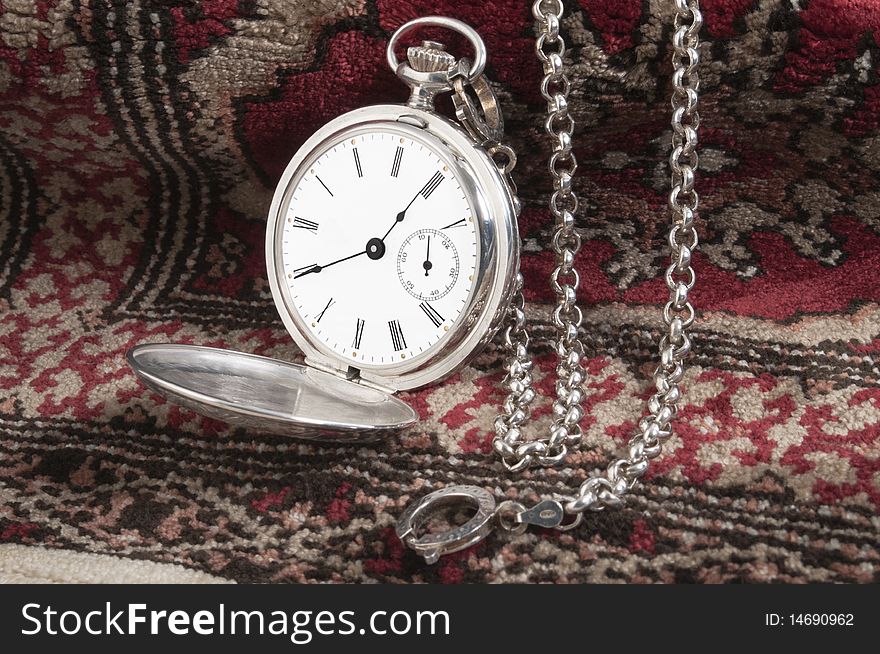 Elegant silver pocket watch over a carpet. Elegant silver pocket watch over a carpet