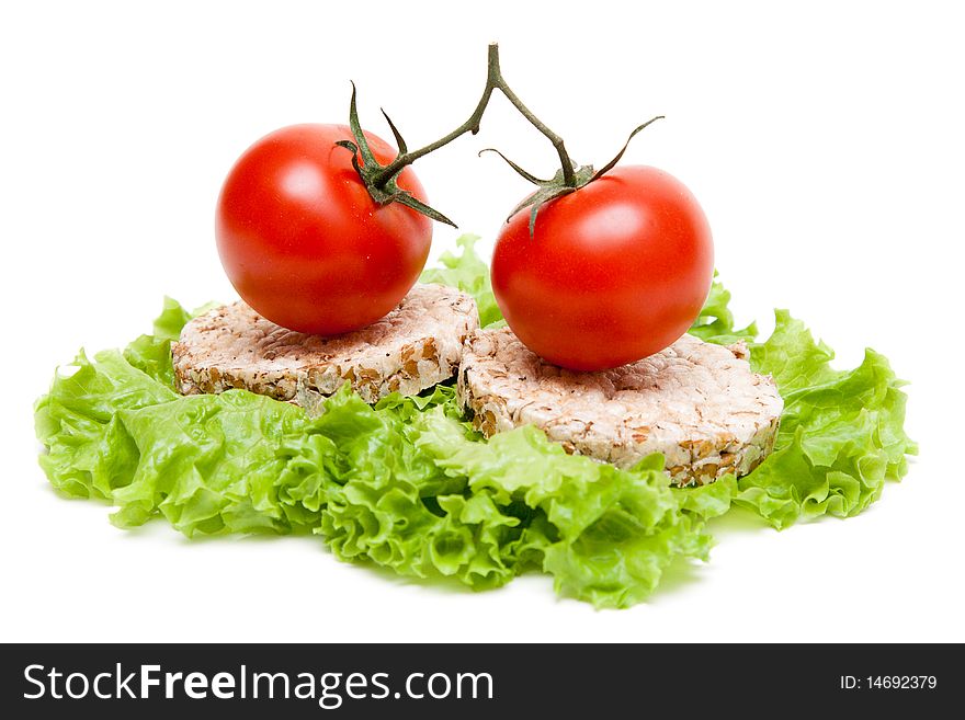 Two ripe tomatoes and small loaf of bread on sheet of the salad