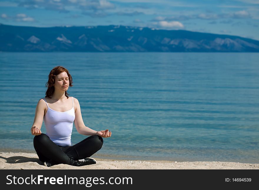 Beautiful girl meditating on the background of mountains on the lake Baikal