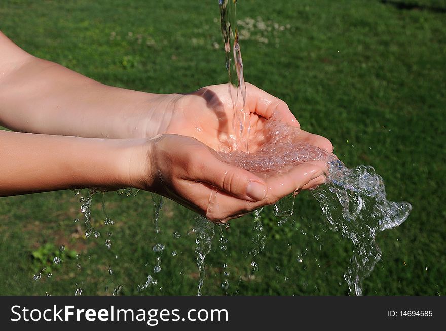 The hands of a young girl and a jet of water