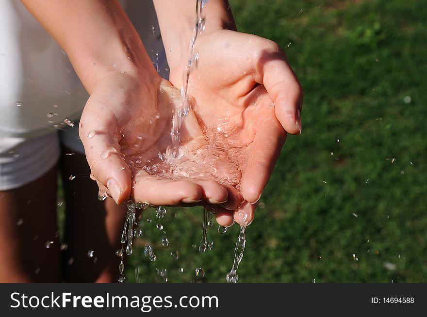 The hands of a young girl and a jet of water