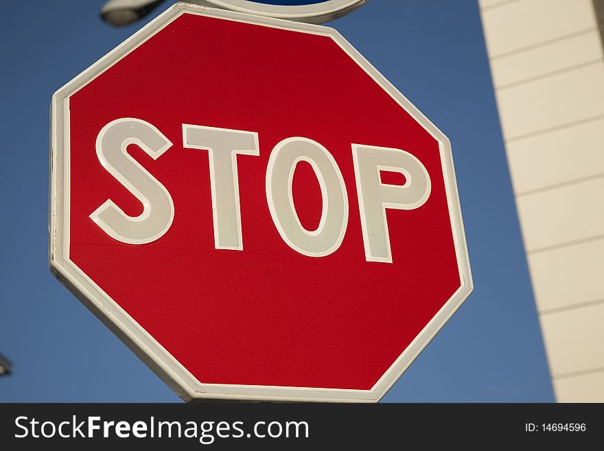 Closeup of red traffic stop sign against clear blue sky background in urban setting. Closeup of red traffic stop sign against clear blue sky background in urban setting