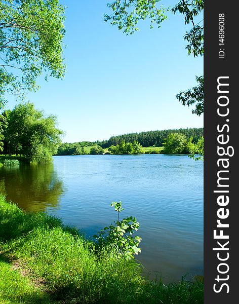 Shows the river, trees, grass and sky.