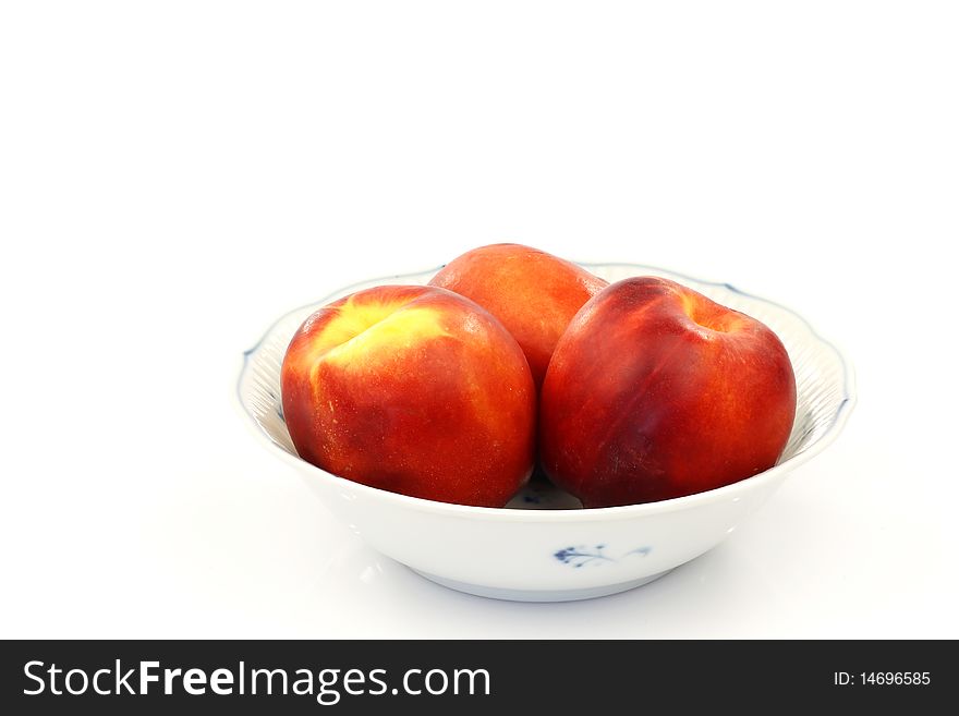 White bowl with three nectarines isolated on white