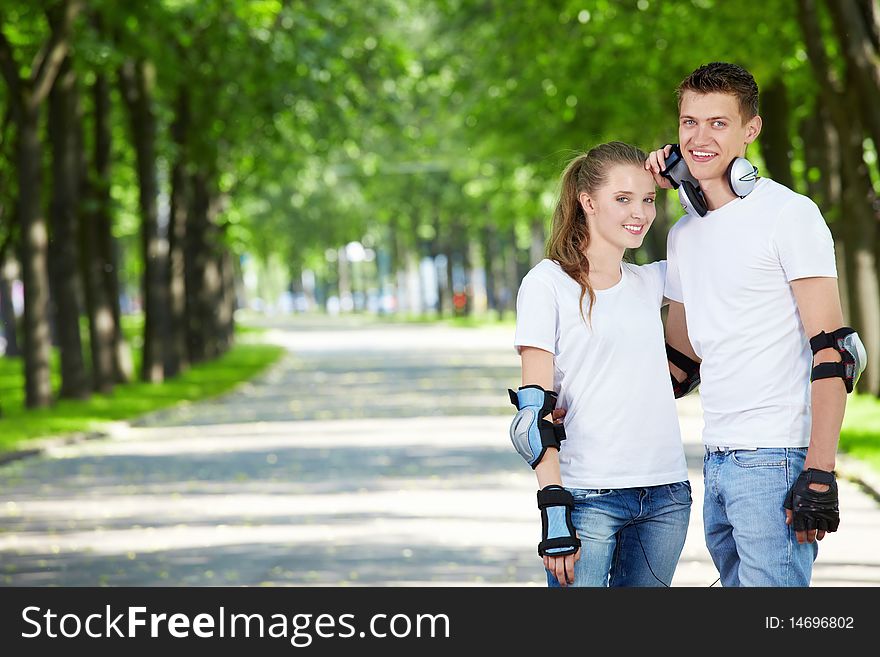 Young enamoured couple on rollers in park. Young enamoured couple on rollers in park