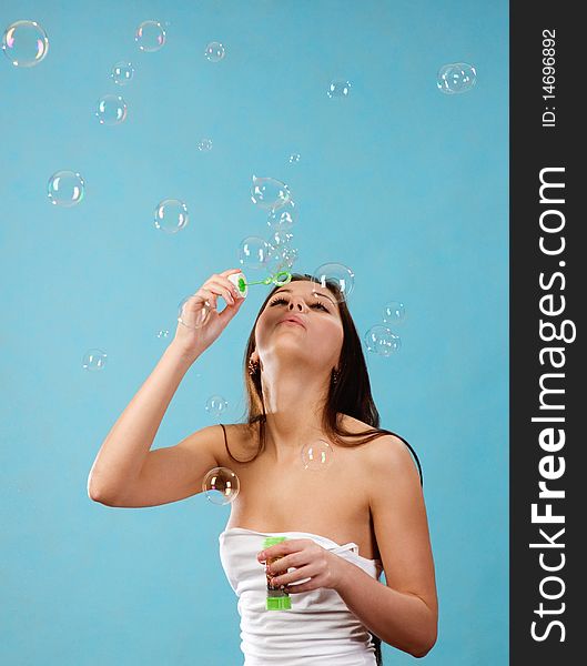 Young woman playing with lots of soap bubbles on a blue background. Young woman playing with lots of soap bubbles on a blue background