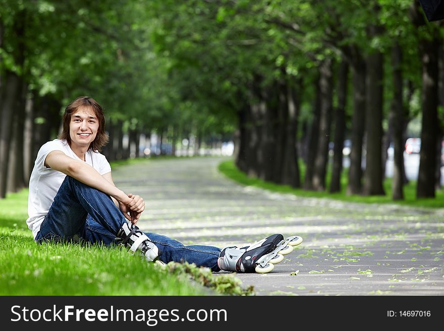 The young man sits on a grass with rollers. The young man sits on a grass with rollers