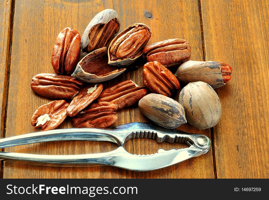 Pecans, whole and broken and Nutcracker lie on the background of a wooden table