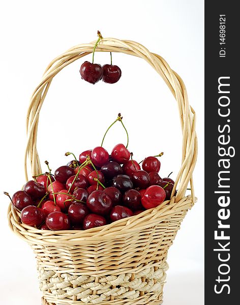 Wicker basket with fresh red cherries on the white background. Wicker basket with fresh red cherries on the white background