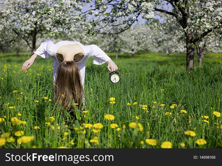 Young Girl With An Alarm Clock Near Blooming Apple