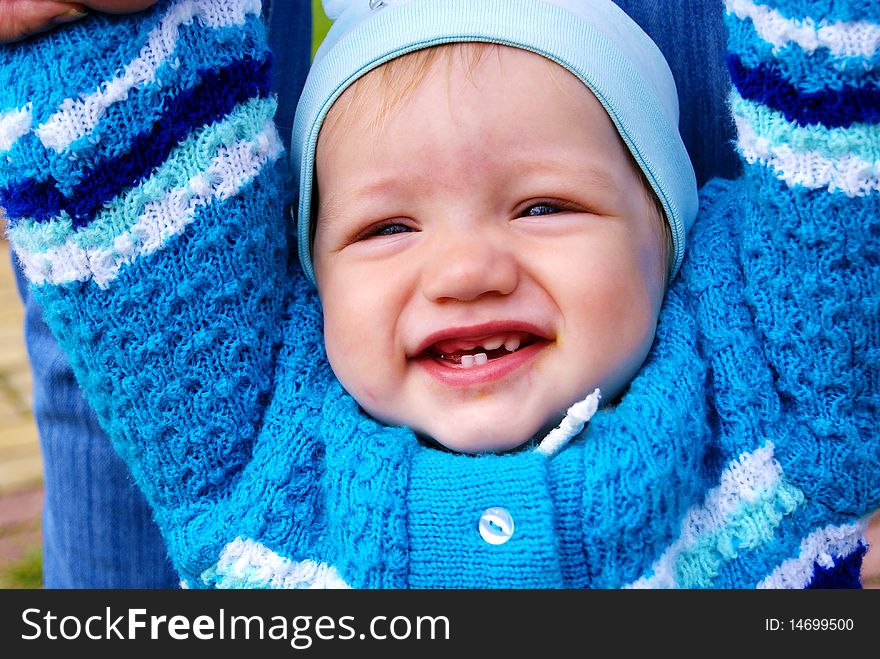 The happy little boy in a dark blue jacket laughs having lifted hands upwards. The happy little boy in a dark blue jacket laughs having lifted hands upwards