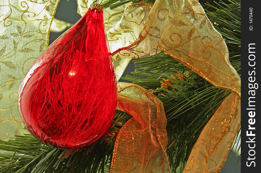 Red teardrop ornament against gold ribbon on Christmas Tree. Red teardrop ornament against gold ribbon on Christmas Tree