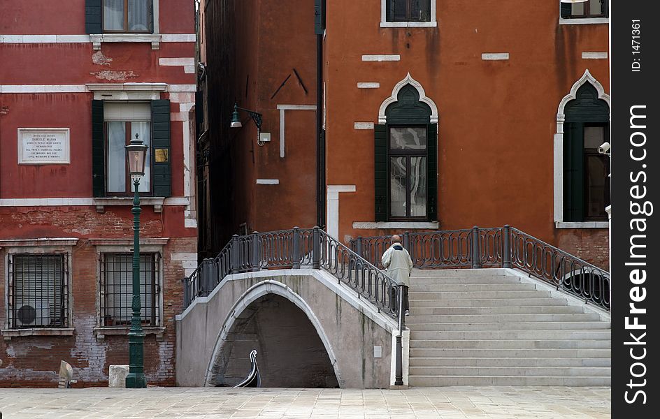 One man walking over a canal bridge in Venice. One man walking over a canal bridge in Venice.