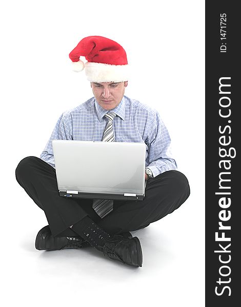 Businessman working on laptop with santa's hat over white. Businessman working on laptop with santa's hat over white