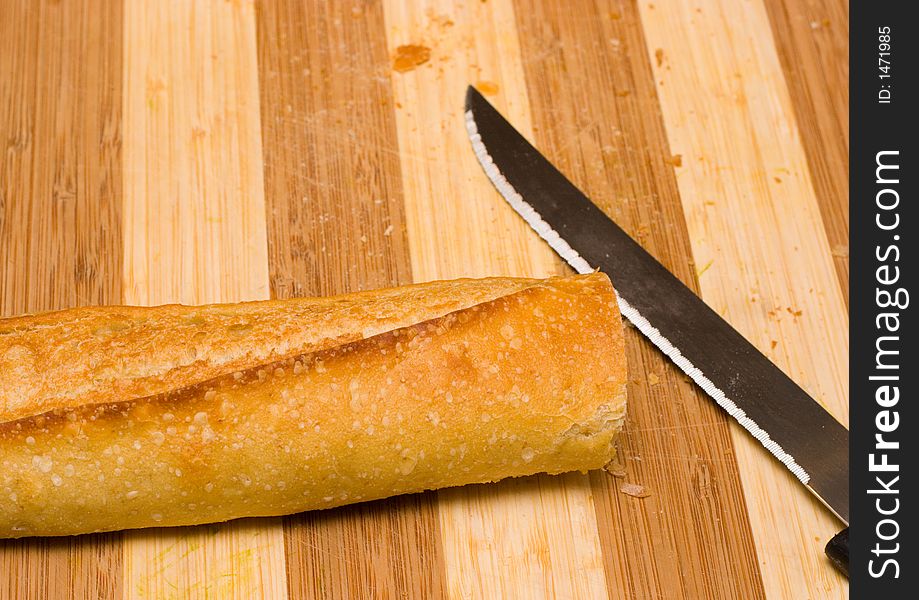 Sourdough baguette on a bamboo cutting board with a knife