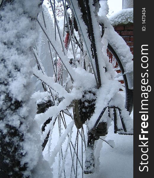Covered with the snow bicycle is standing outdoors in the cold. Covered with the snow bicycle is standing outdoors in the cold.