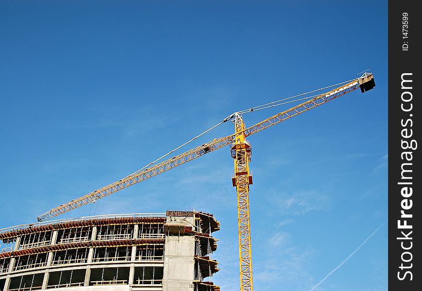 Raw concrete building and yellow jib crane. Raw concrete building and yellow jib crane
