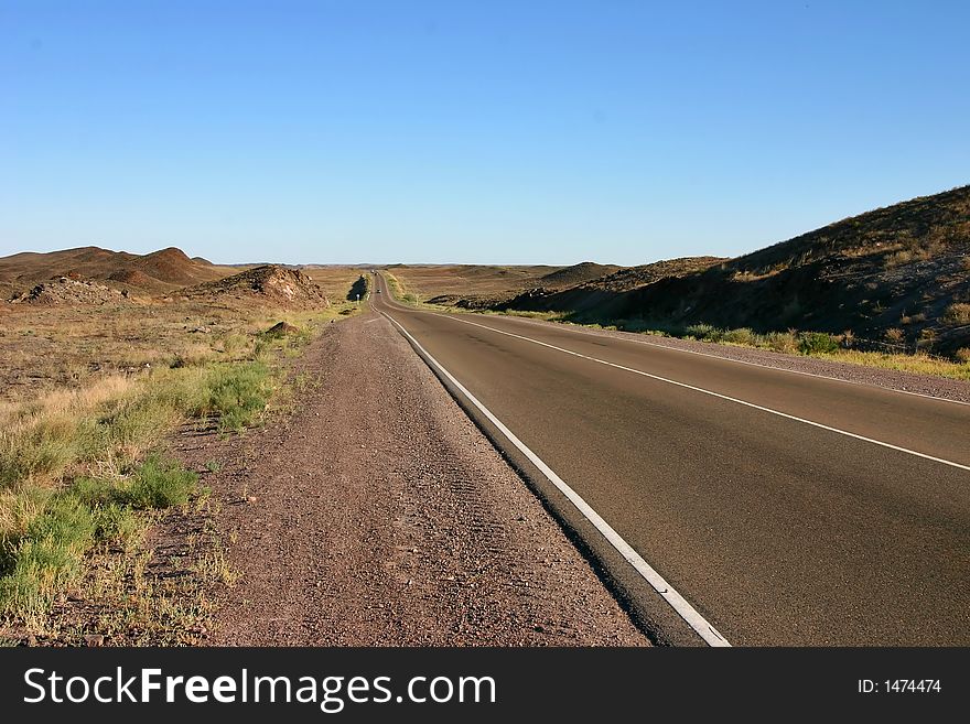 Asphaltic road in a prairie by a hot canicular day