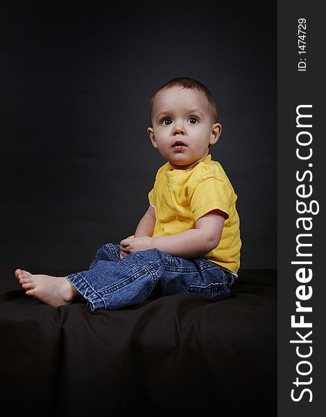 Beautiful baby boy poses on a black background