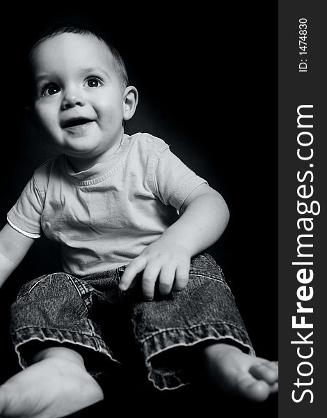 Beautiful baby boy poses on a black background