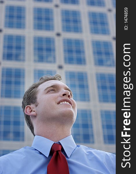 Businessman standing in front of a business building with a toothy smile and a red tie with a blue shirt. Businessman standing in front of a business building with a toothy smile and a red tie with a blue shirt