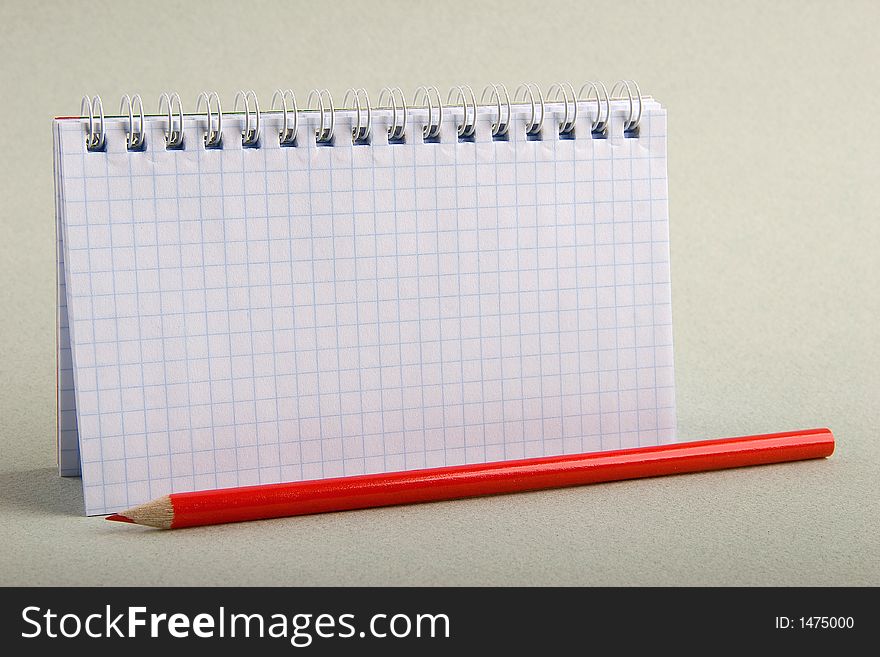 Notebook in a cell with a red pencil. Notebook in a cell with a red pencil