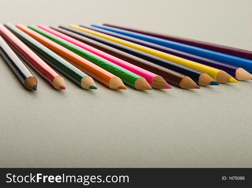 The multi-coloured wooden pencils scattered on an art paper.