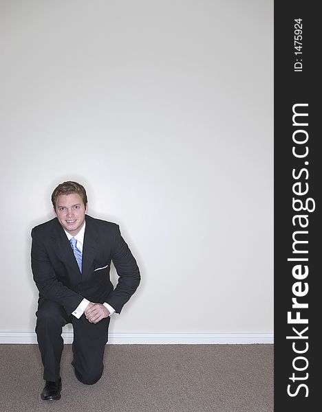 Businessman kneeling on one knee showing his determination while wearing a full suit against a white background