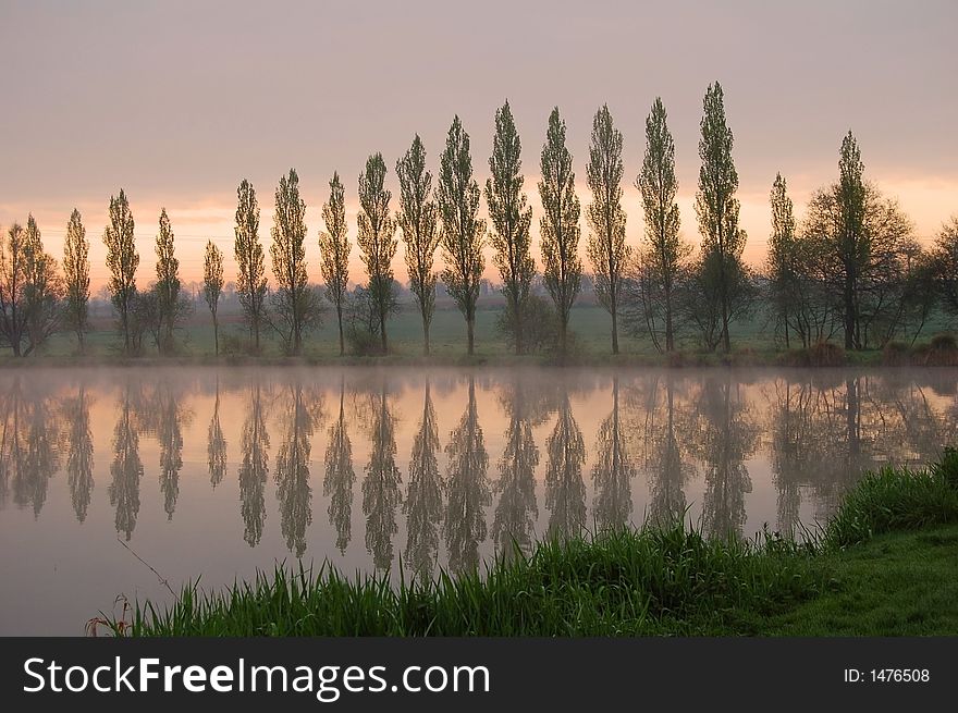 Dawn and trees reflecting in a like, early morning in Brittany (France). Dawn and trees reflecting in a like, early morning in Brittany (France)