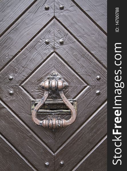 Steel medieval knocker on the old wooden historic door