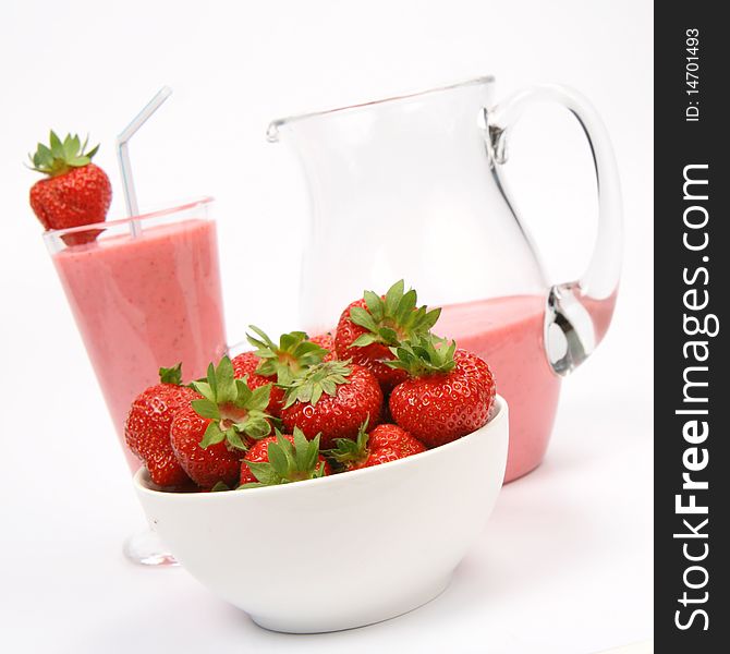 Strawberries in a bowl and a strawberry shake in a glass with a straw and in a jug on white background. Strawberries in a bowl and a strawberry shake in a glass with a straw and in a jug on white background