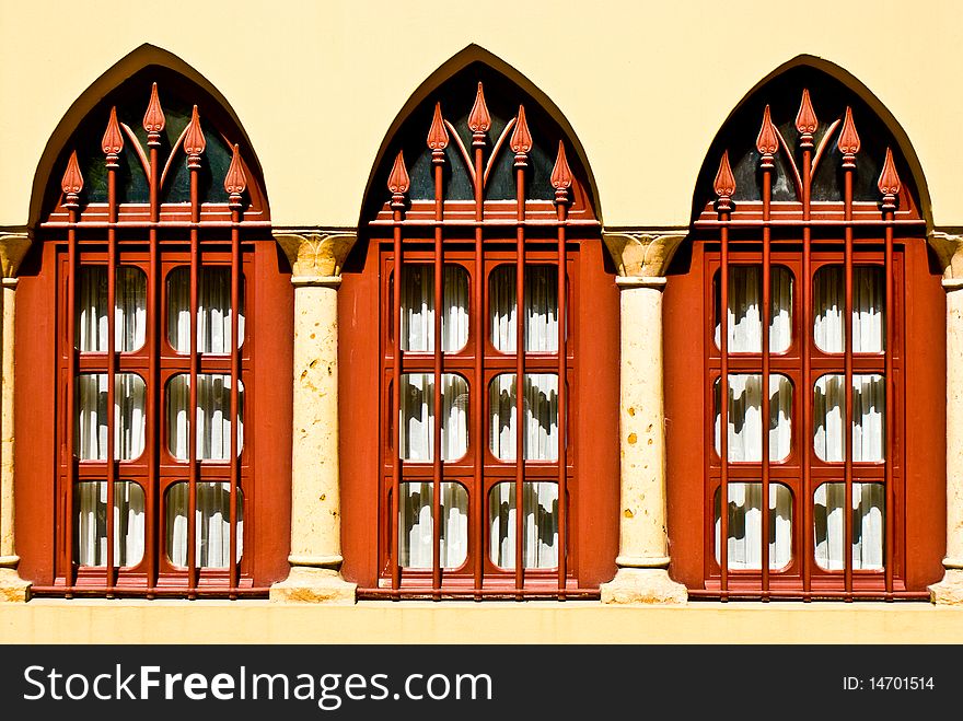 Three red windows ona still wall with archs. Three red windows ona still wall with archs